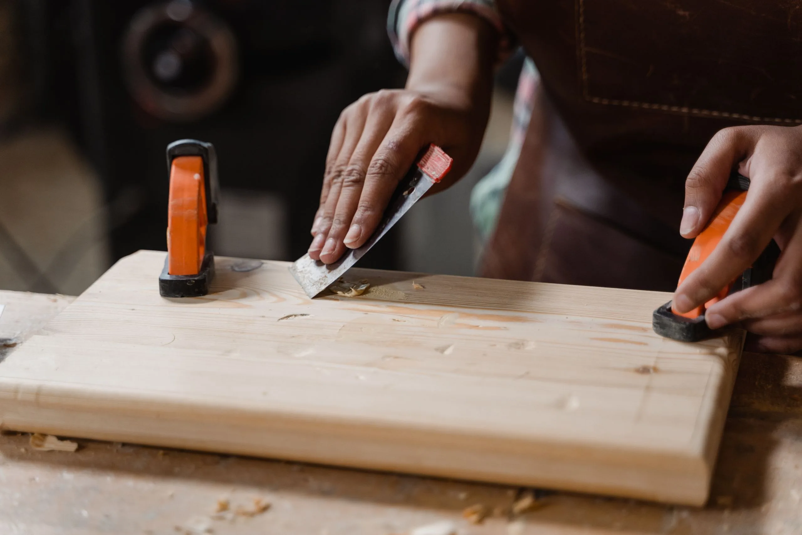 Mains encollant une pièce de bois maintenue par des serre-joints sur un établi d'atelier