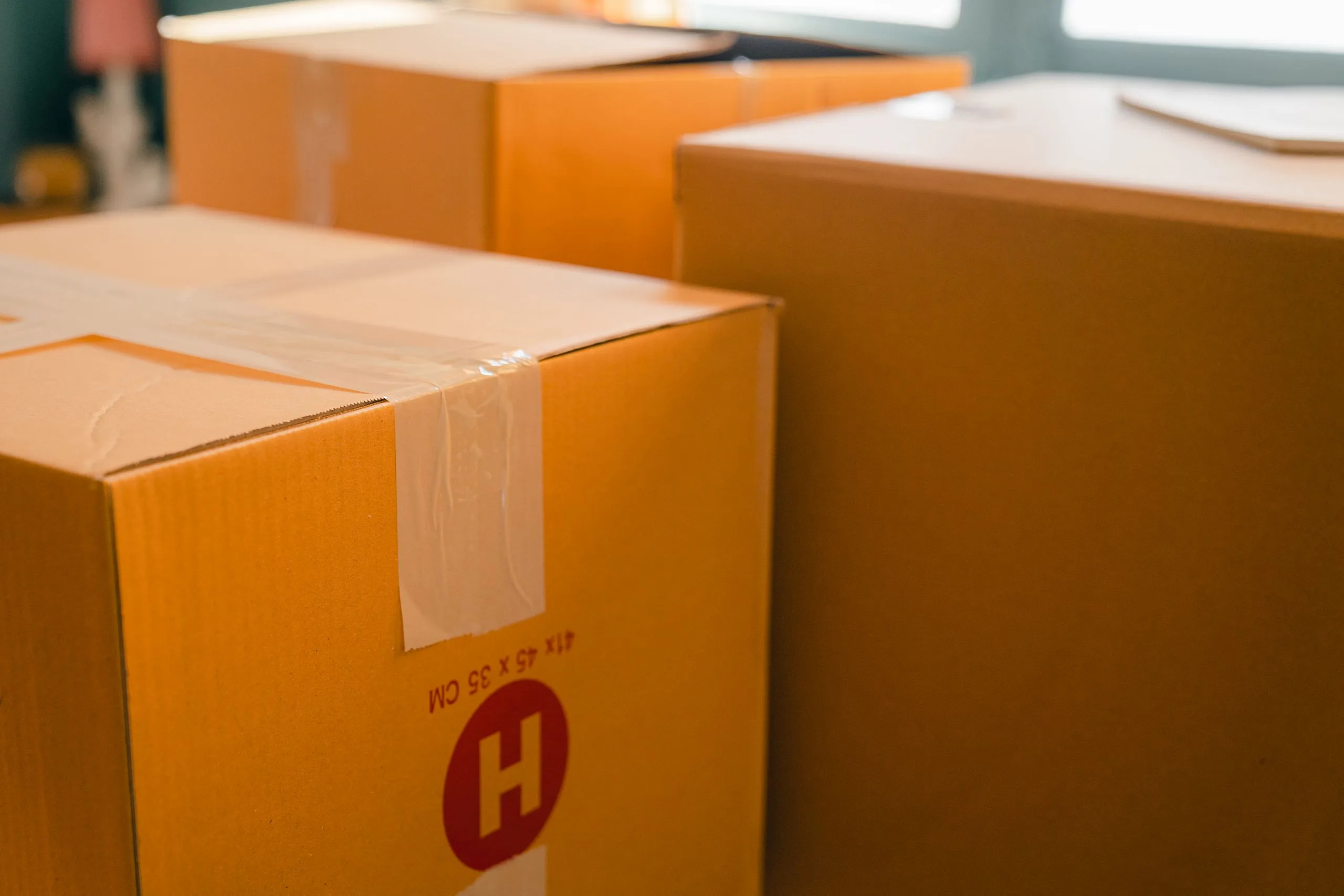Cartons de déménagement empilés près d'une fenêtre dans une pièce baignée de soleil