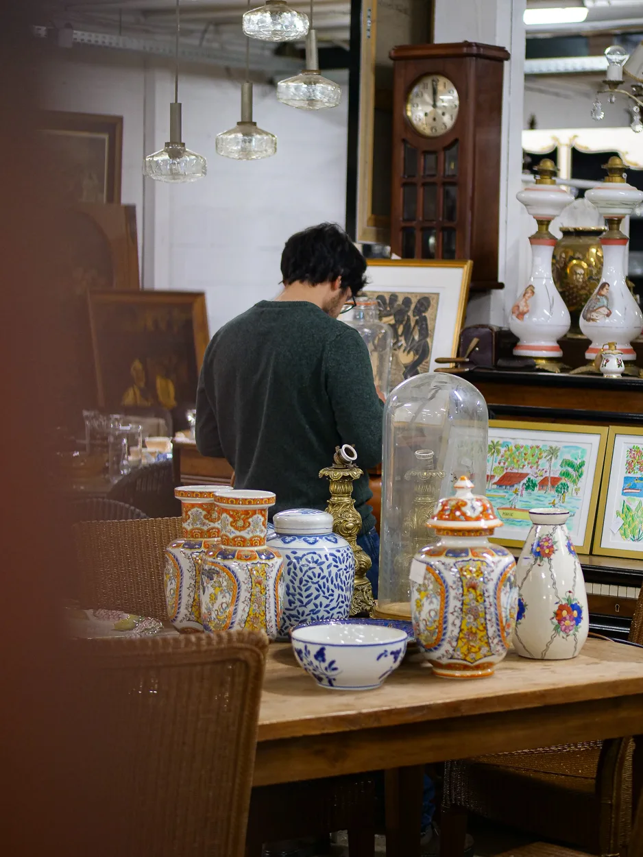 Conseil à un client devant les vases en porcelaine et lampes à pétrole