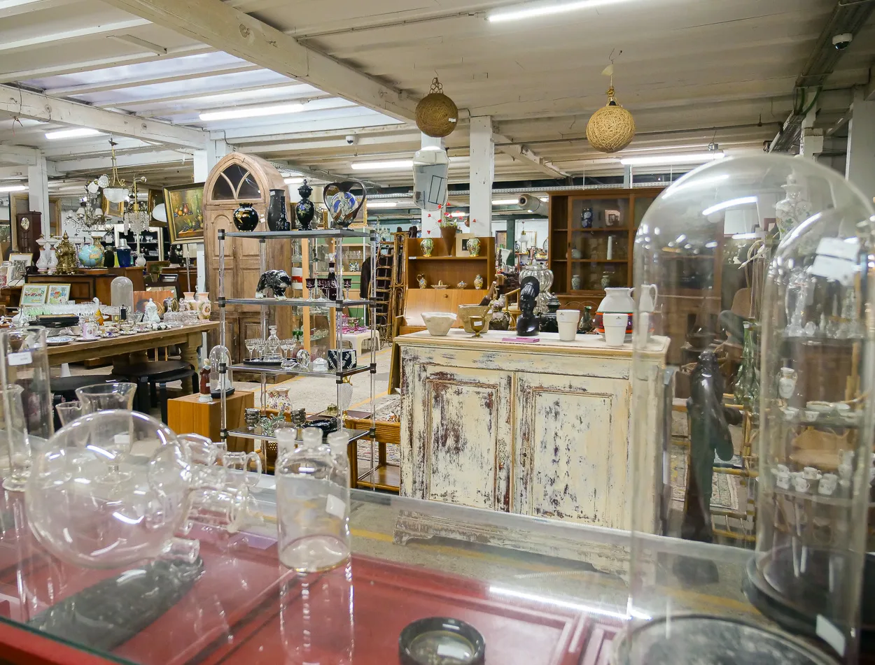 Allée du dépôt d'antiquités avec vitrines, globes et buffet patiné