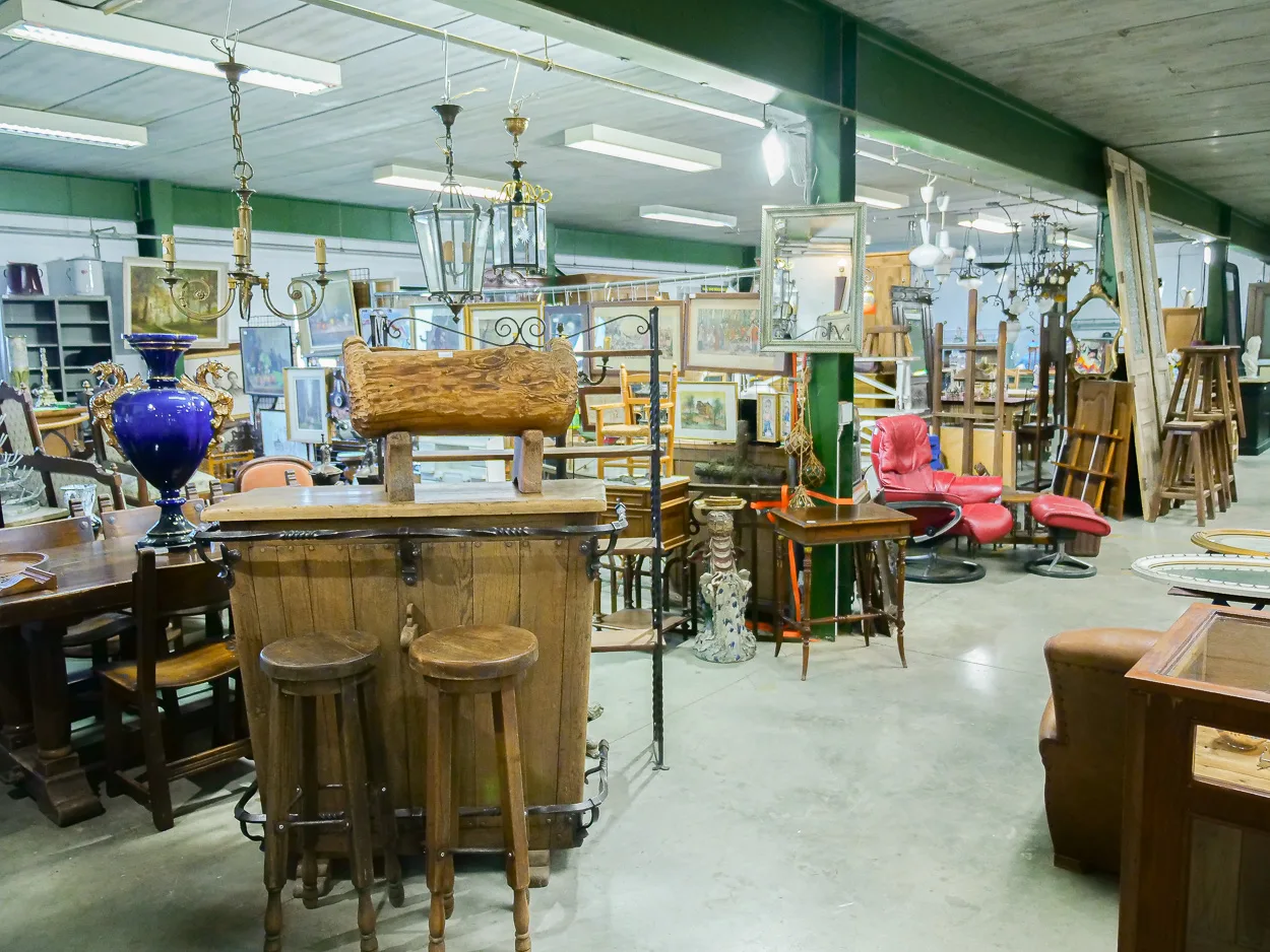 Vue large du dépôt d'antiquités avec ancien bar en chêne, fauteuils et tableaux