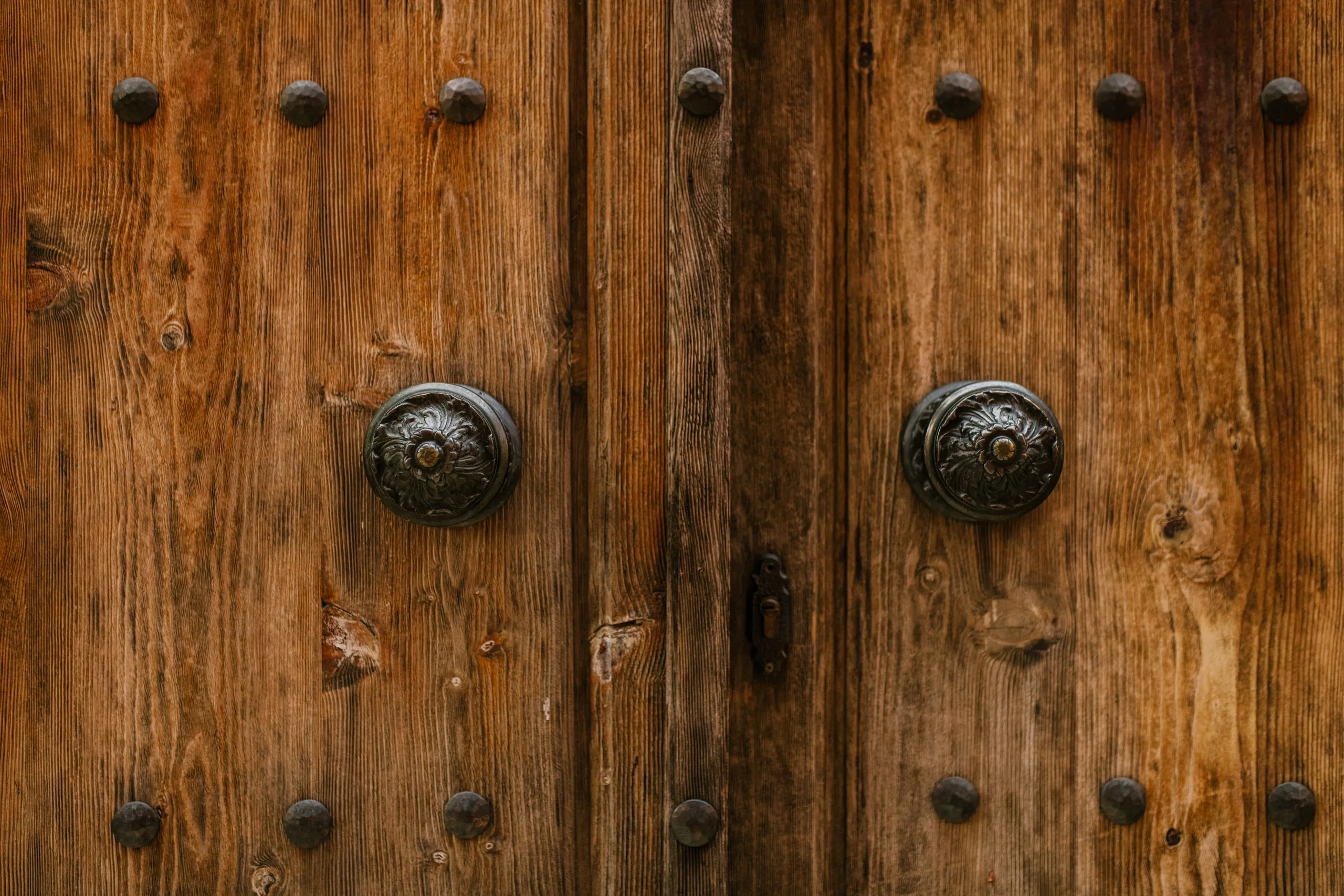 Gros plan sur une boiserie ancienne patinée et ses poignées en métal ouvragé