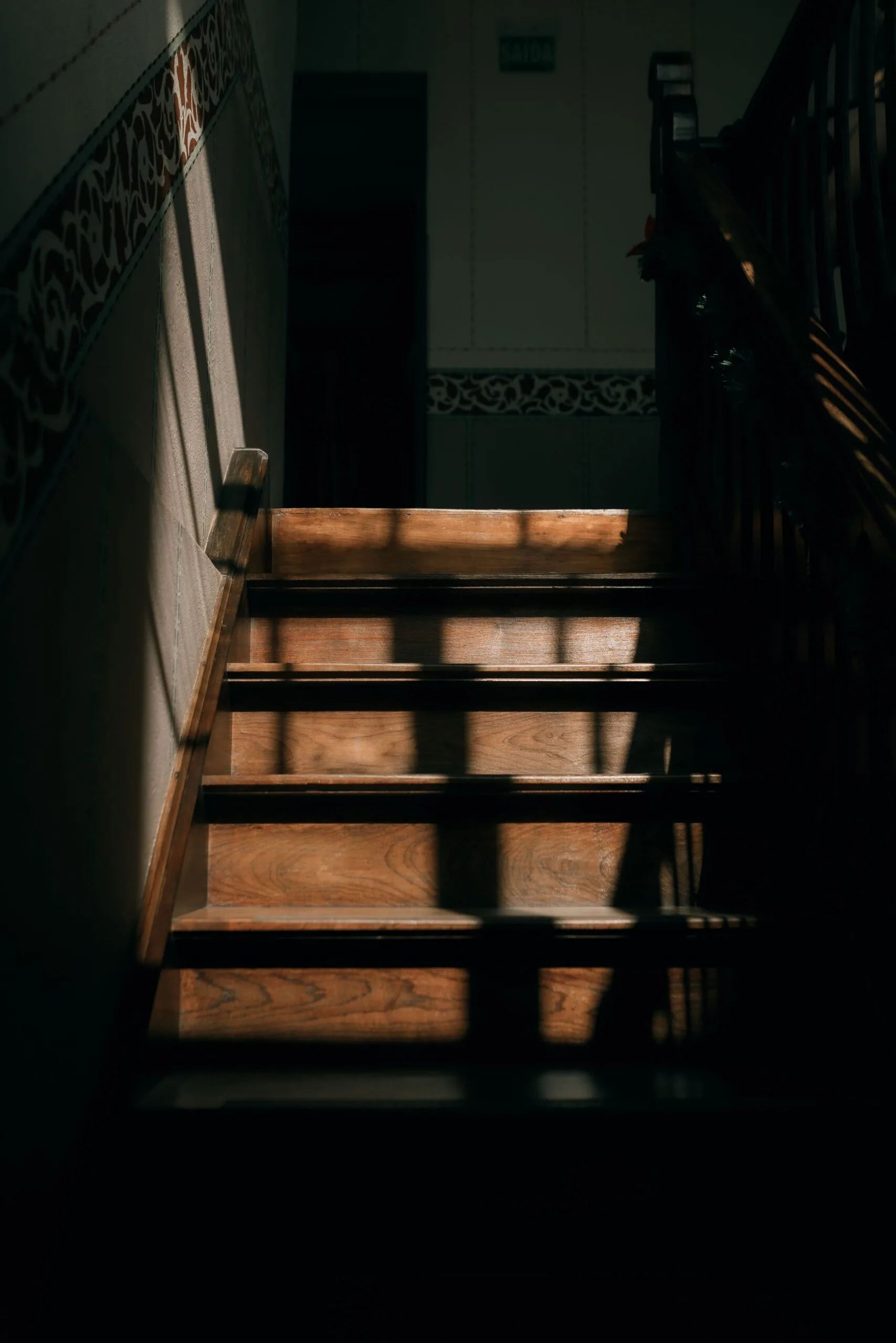 Escalier en bois ouvragé d'une maison ancienne, éclairé par une douce lumière naturelle
