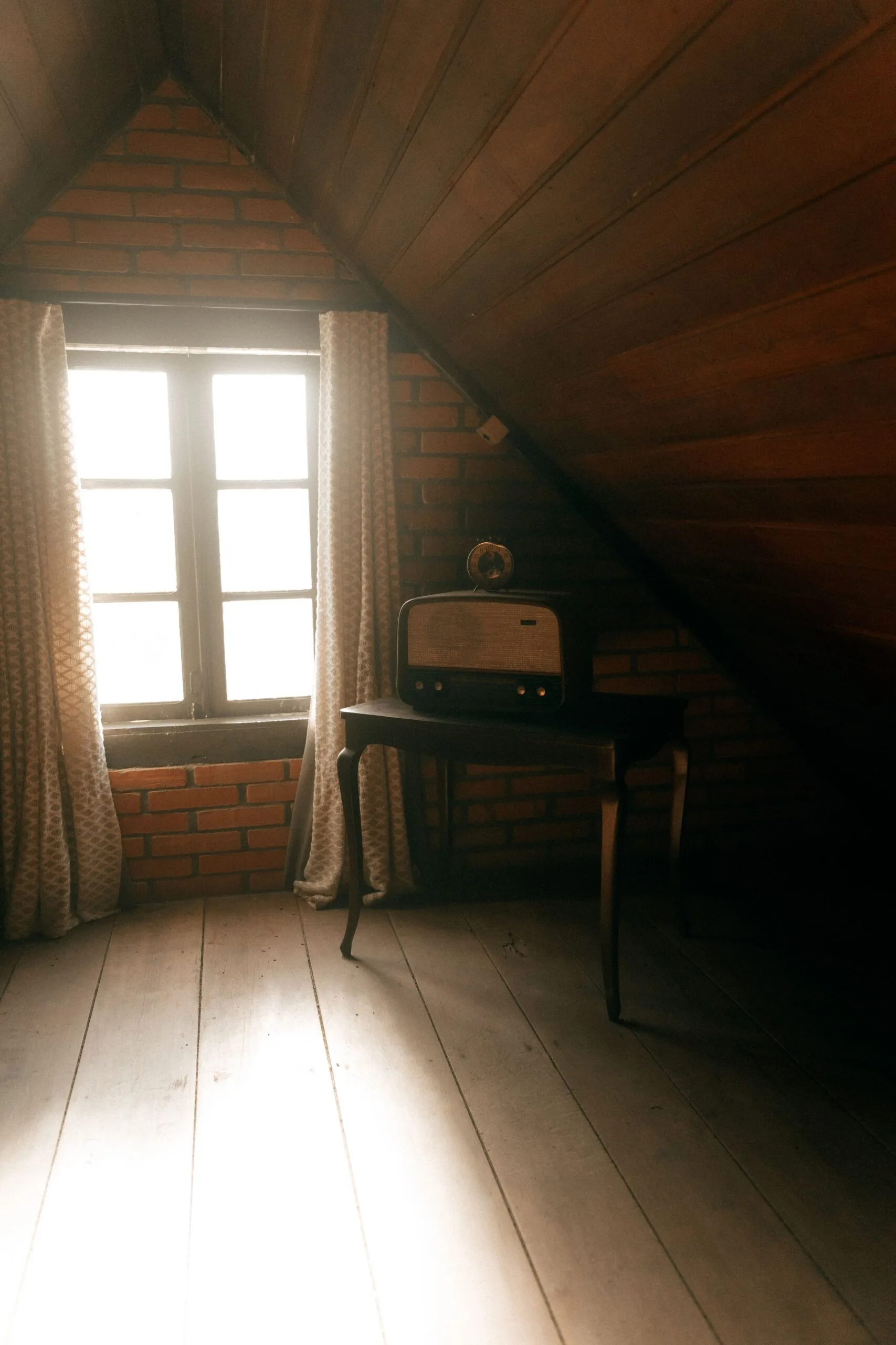 Grenier ancien baigné de lumière chaude avec une radio d'époque posée près de la fenêtre