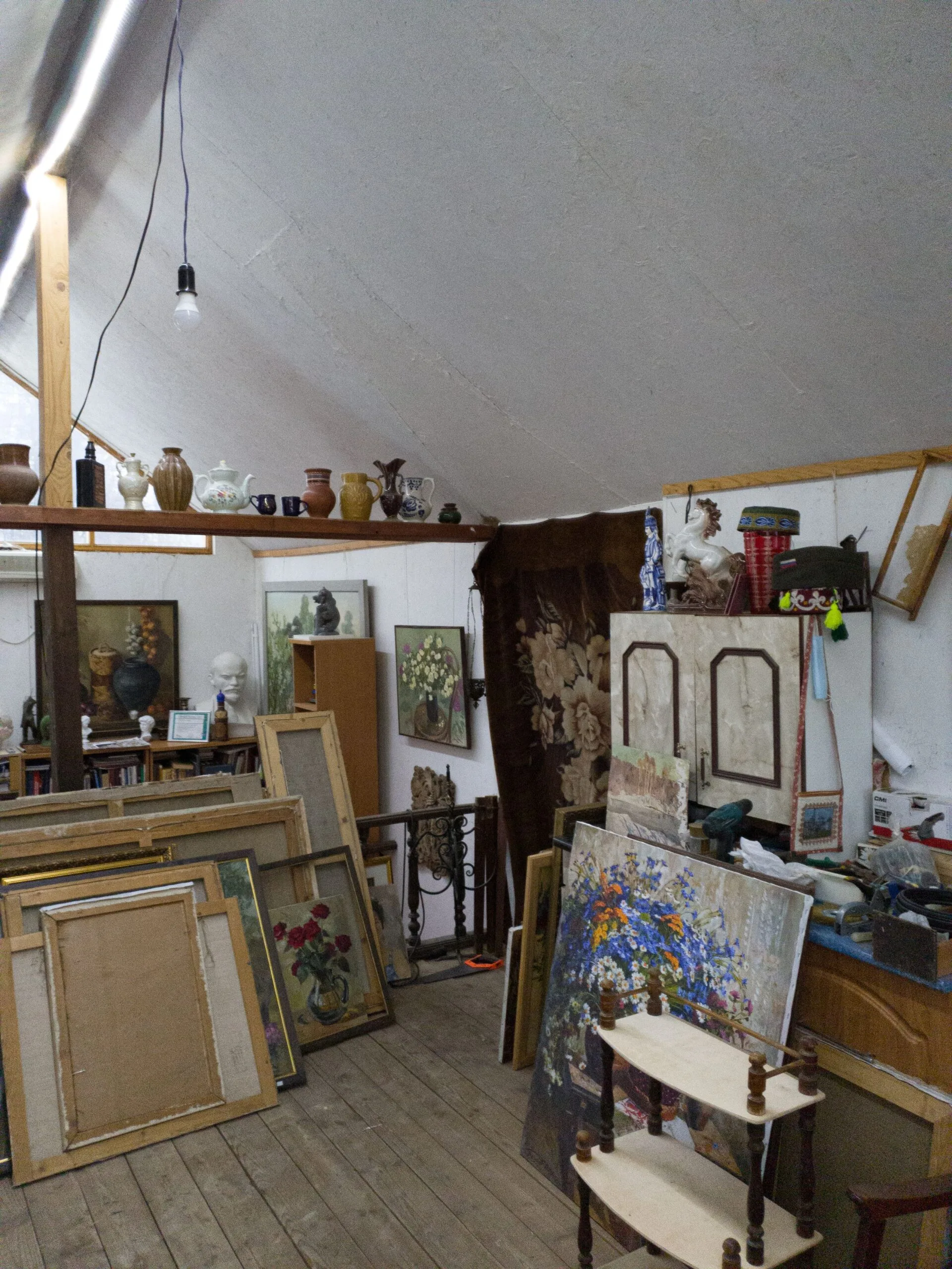 Grenier de maison de famille encombré de tableaux anciens, meubles et objets d'antiquité
