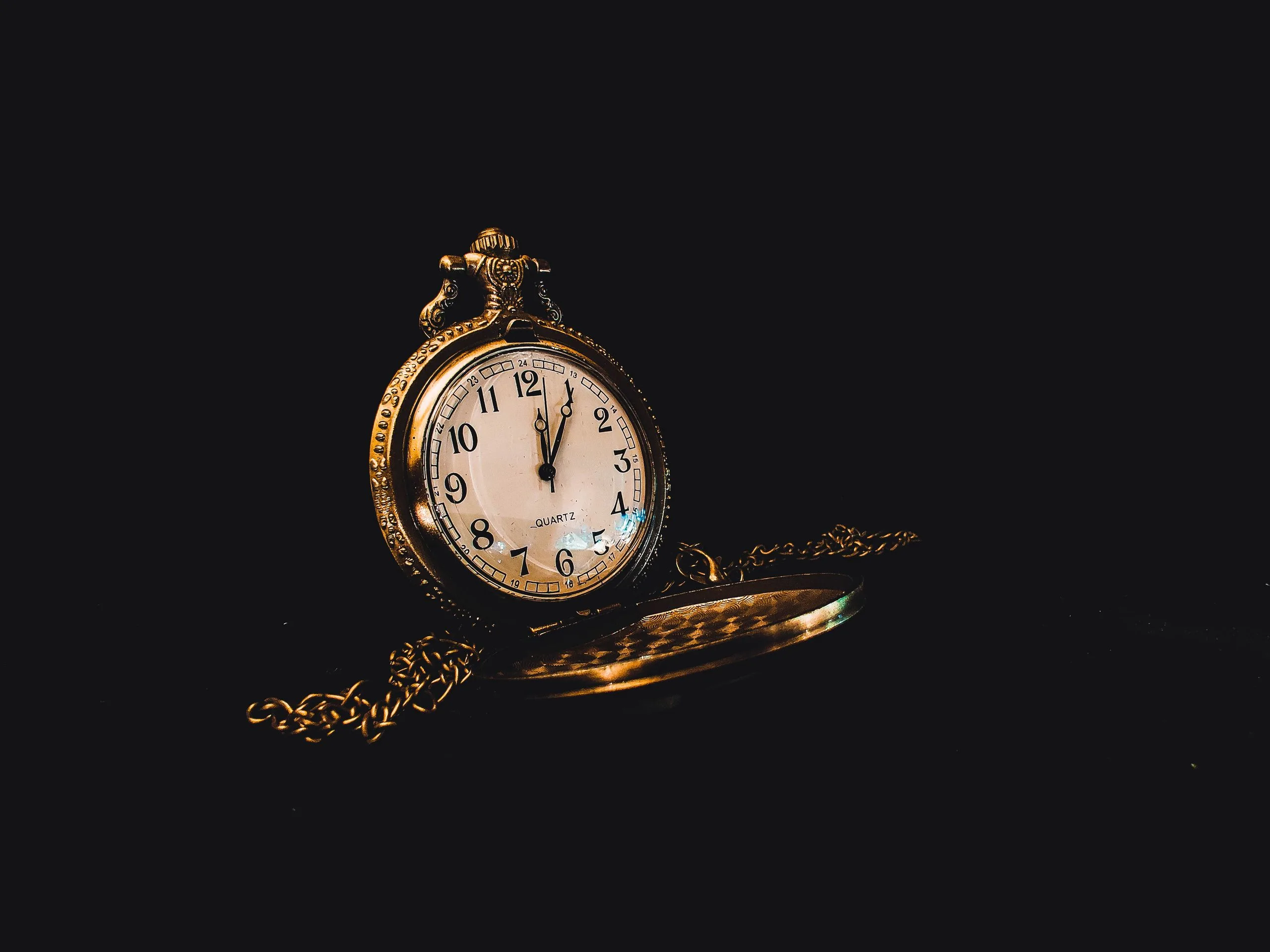 Montre à gousset ancienne au cadran ouvragé et sa chaîne, dans une lumière tamisée