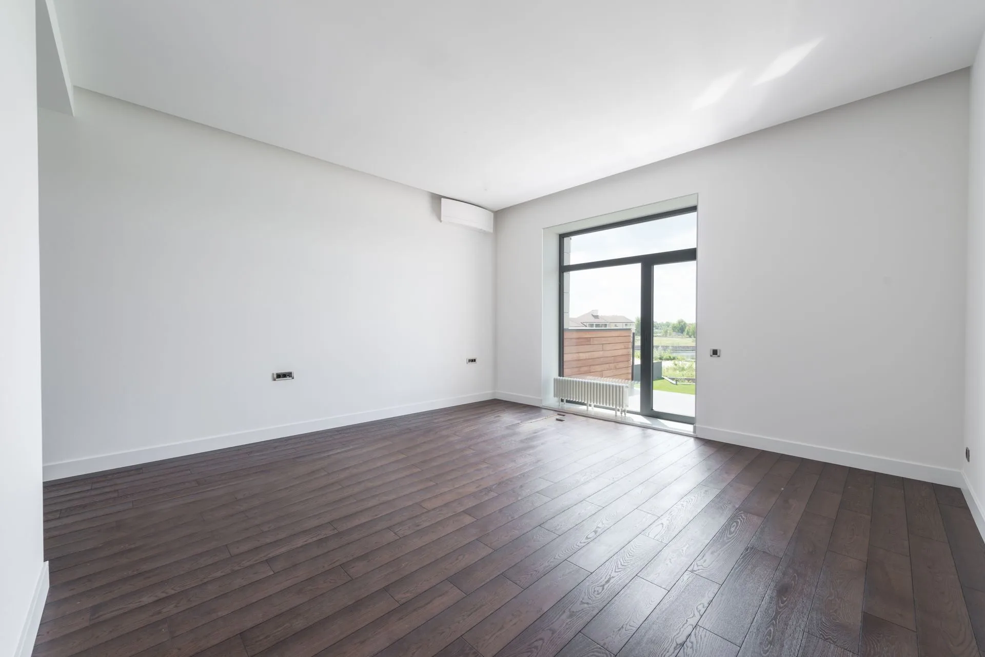 Pièce vide et lumineuse avec parquet en bois foncé