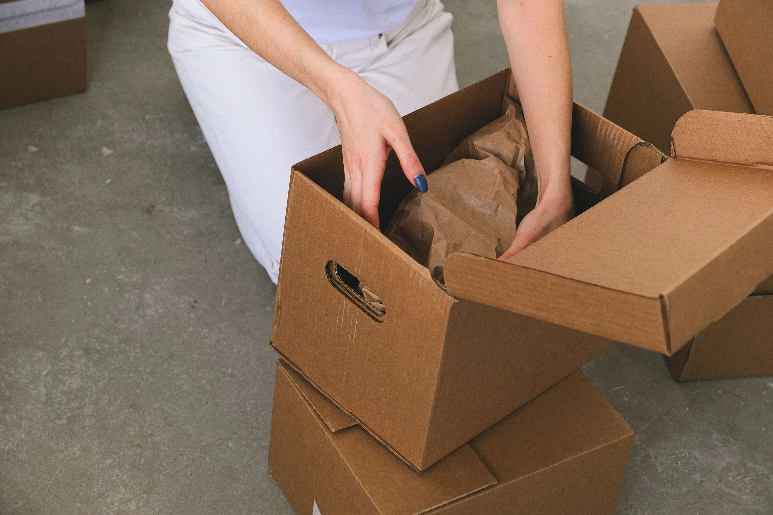 Mains emballant des affaires dans un carton lors du tri d'une maison avant déménagement